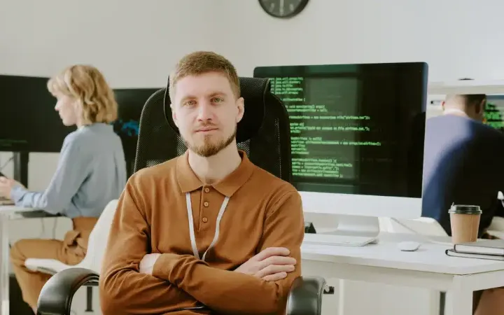 Informatikus az irodában, mögötte munkaállomások