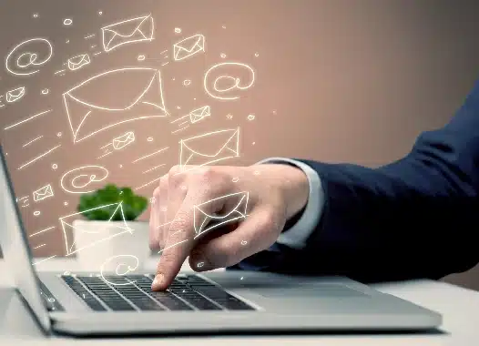 Kéz egy notebook billentyűzetén, körülötte rajzolt borítékok és e-mail-ikonok